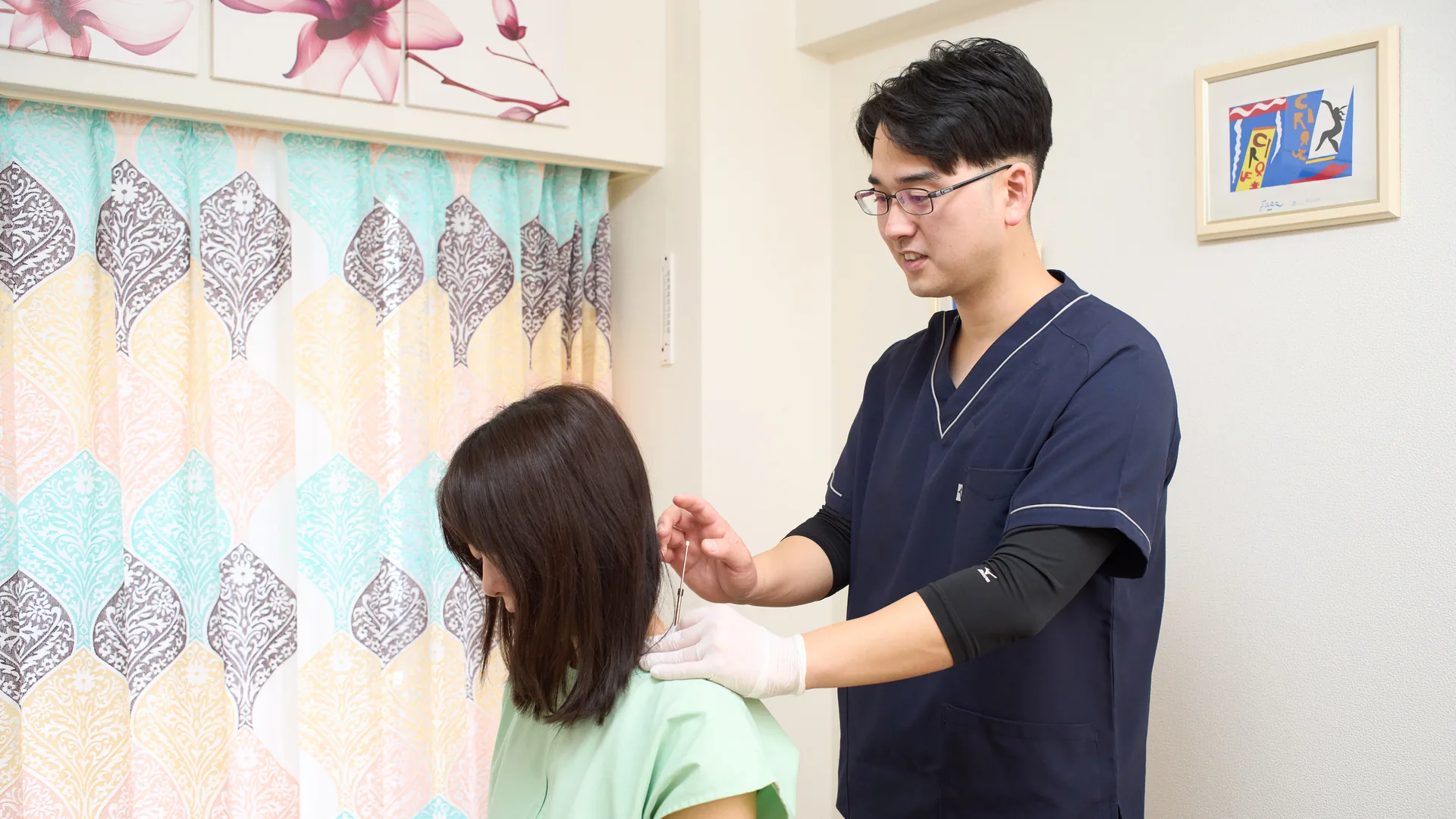 鍼灸師が座った方の肩に鍼をする様子